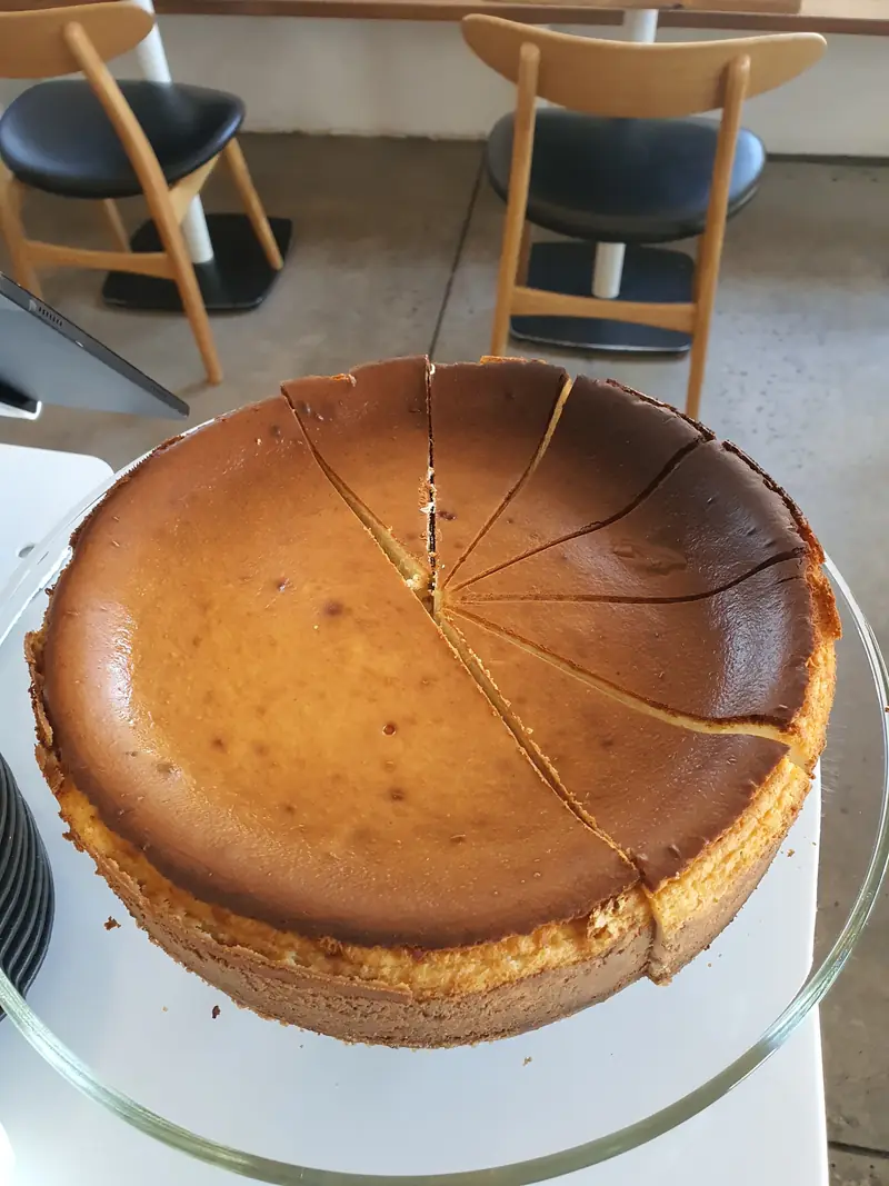 A whole baked cheesecake on a glass cake stand
