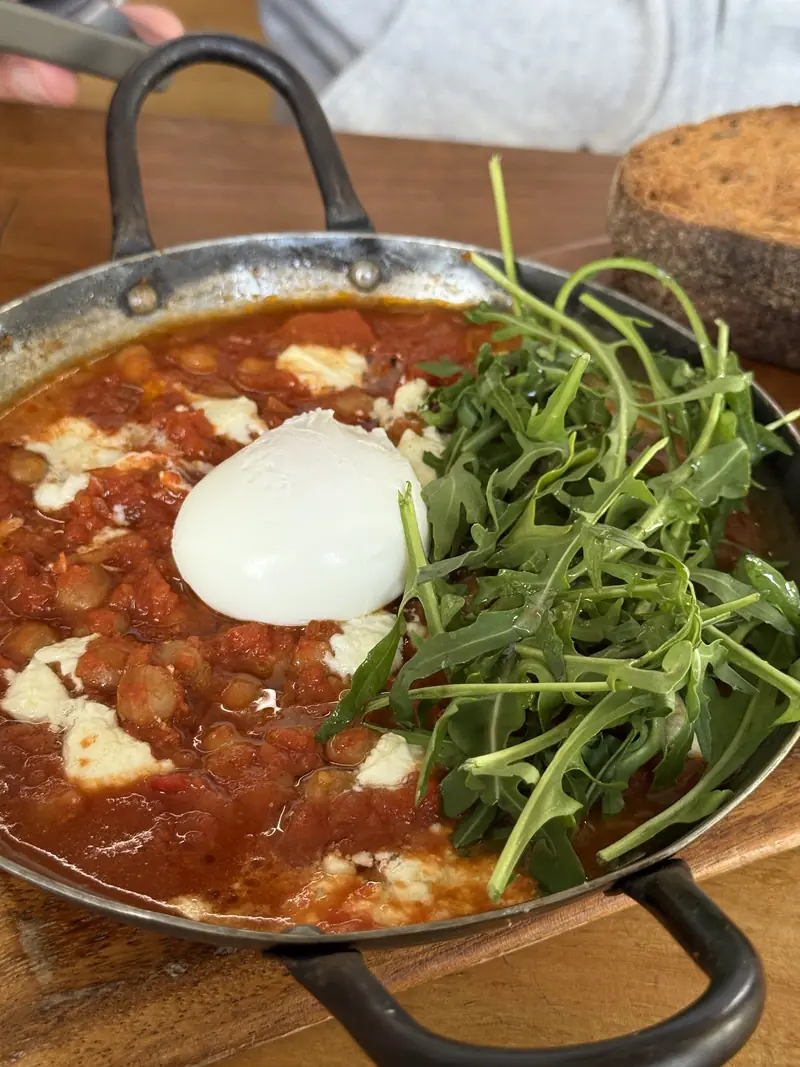 Chickpea bake in a cast pan with a poached egg, rocket and toasted sourdough